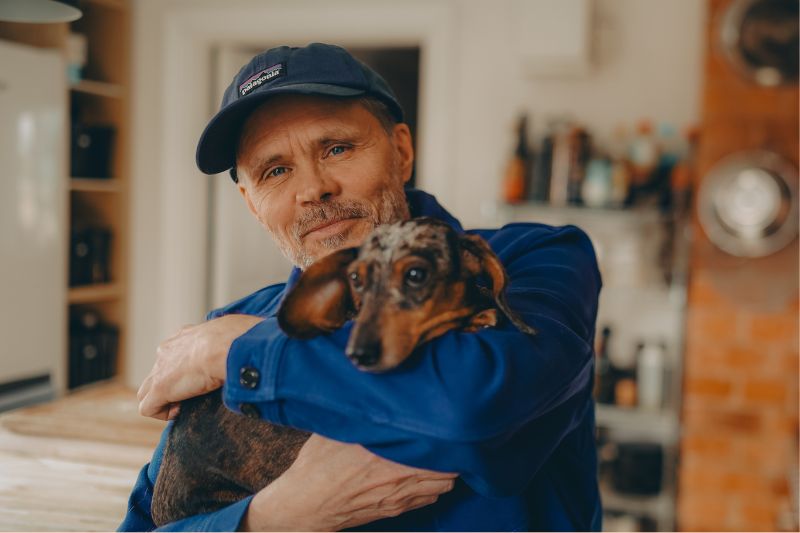 konstnären Mikael Genberg står med sin tax i famnen, i virsbo. i Sitt sommarcafe, Genbergs sommarcafe.