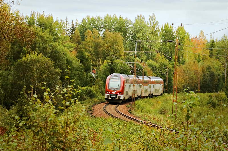 Tåg i Bergslagens dubbeldäckare ER1 på spåret i en skogsmiljö.